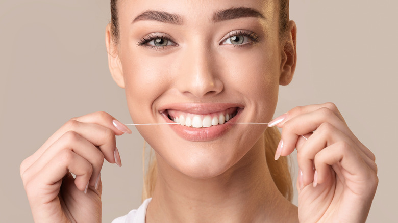 woman smiling and flossing teeth