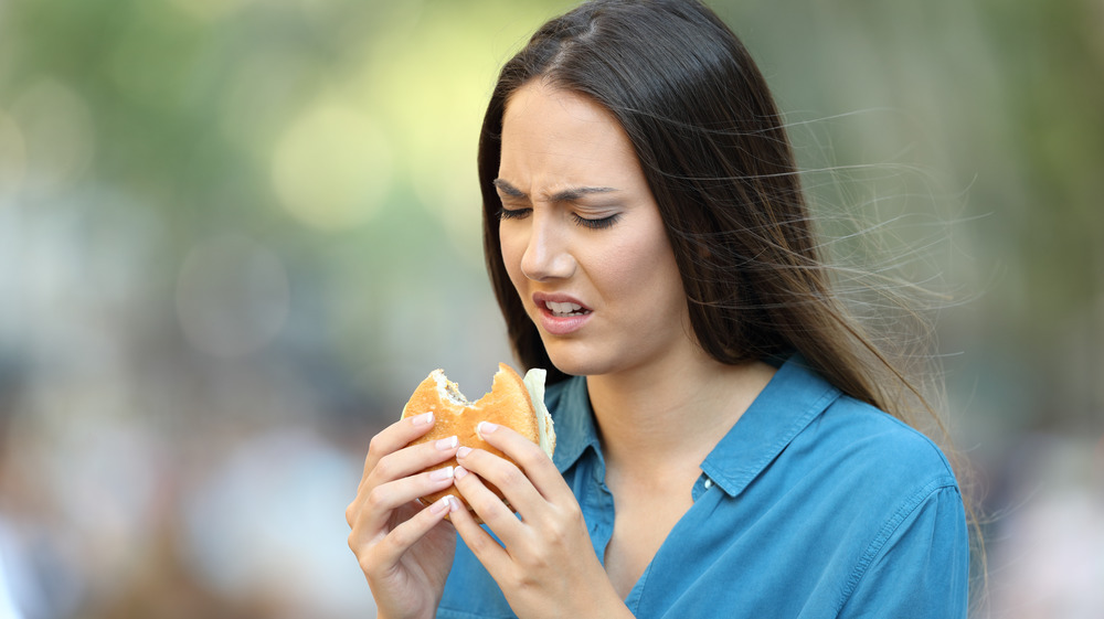 A woman who is disgusted by her hamburger 