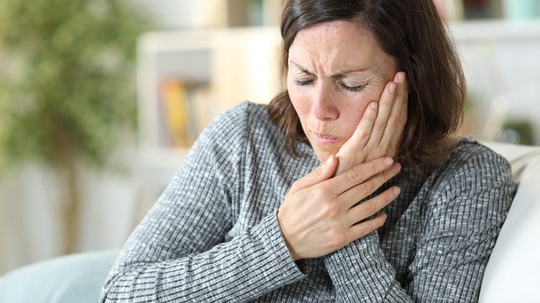 woman holding jaw in pain