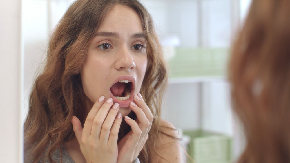 A woman inspecting her mouth 