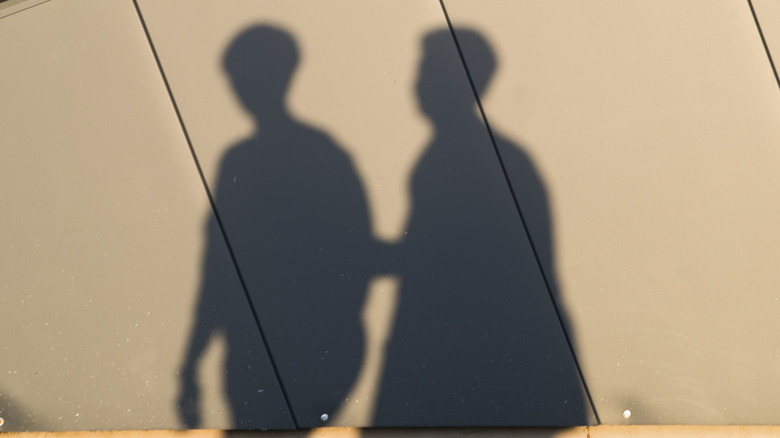 Shadows of two people, one grabbing the other 