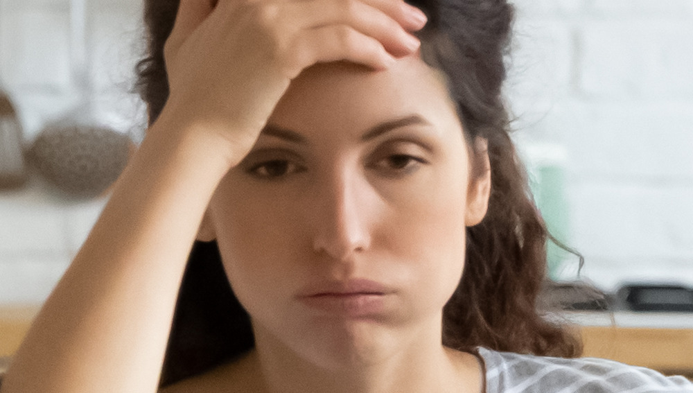 A woman holding her head and looking distressed 