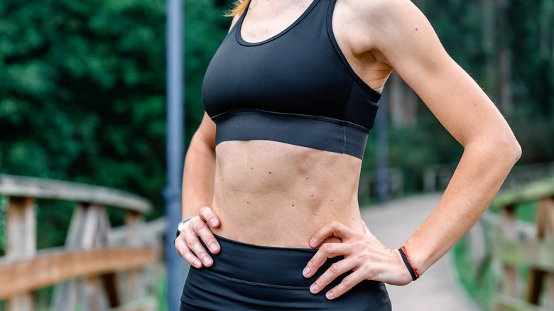 Woman wearing a workout outfit with moles on her stomach