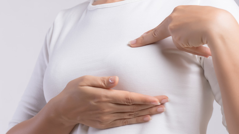 Woman in long sleeve shirt checking her breast for lumps