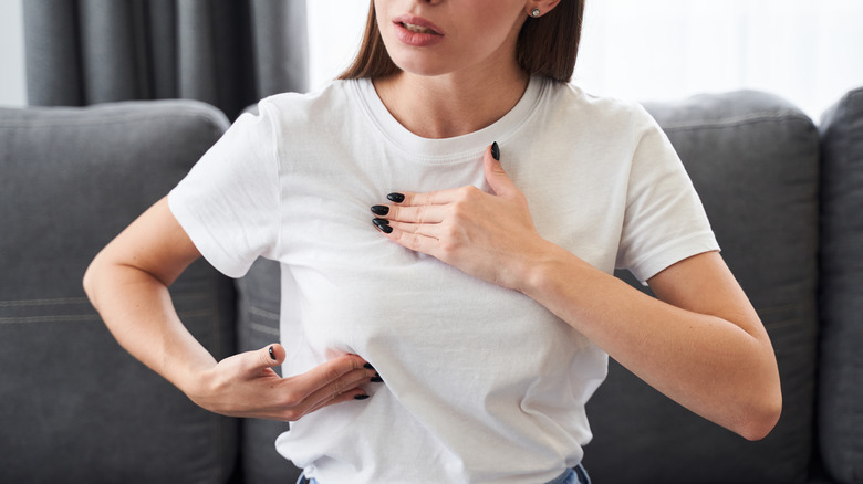 Woman in white t-shirt checking her breast