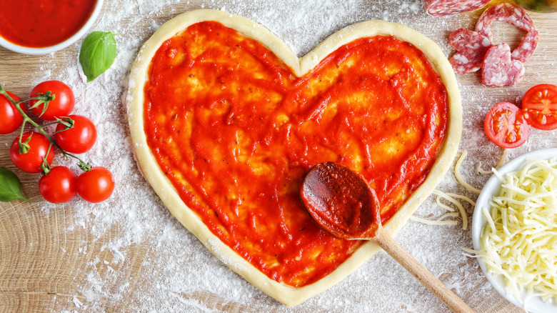 Heart-shaped pizza dough with sauce