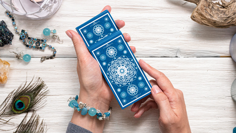 Person shuffling tarot cards on a table