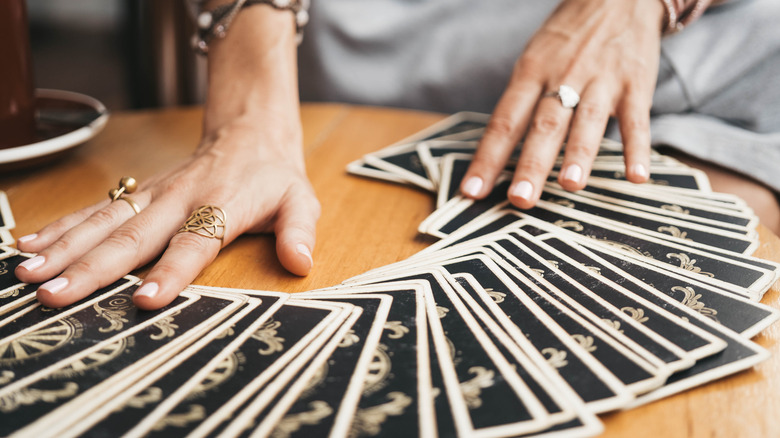 Hands spreading out cards on table