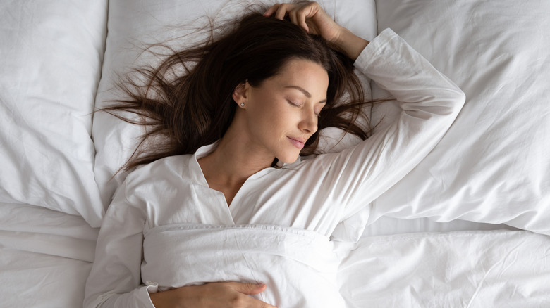 Woman sleeping in all white bedding