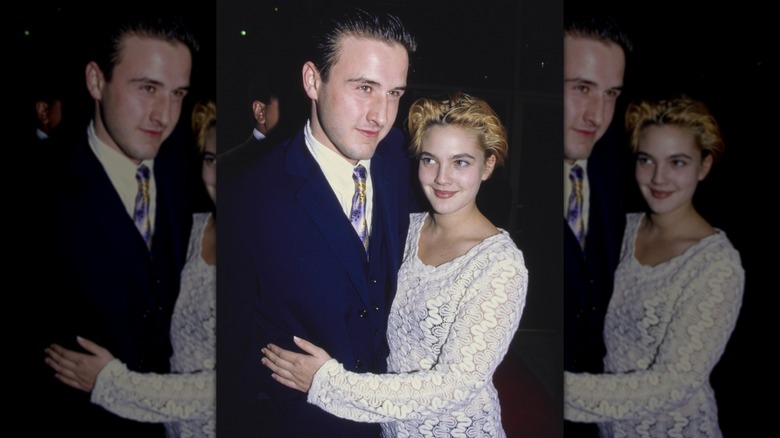 Drew Barrymore resting her hand on David Arquette's side together at a movie premiere in 1991