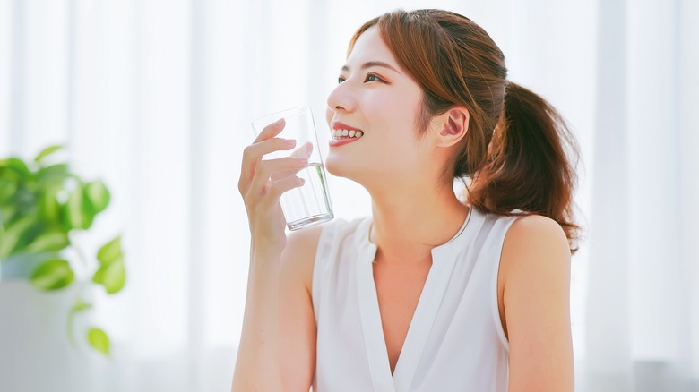 Woman smiling while drinking a glass of water