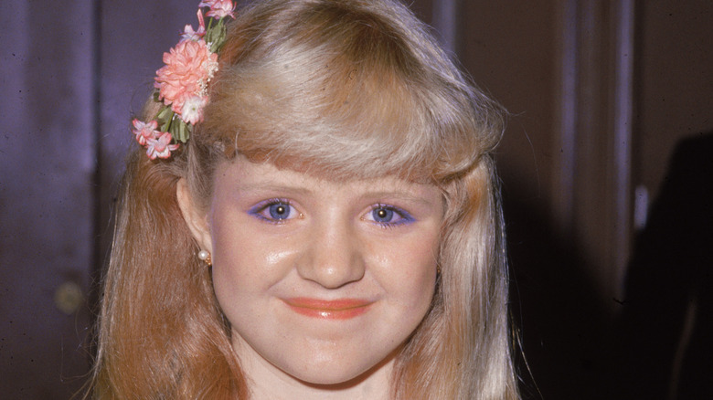 Tina Yothers smiling and wearing flowers in her hair in the early 1980s