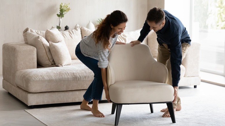 happy man and woman moving armchair