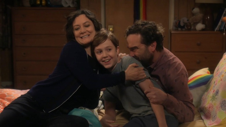 Sara Gilbert and Johnny Galecki embrace Ames McNamara while filming an episode of "The Conners."