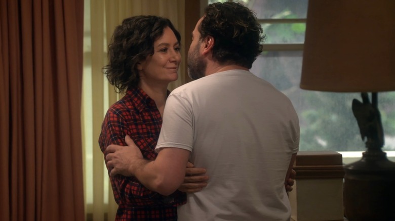 Sara Gilbert smiles at Johnny Galecki as he embraces her while filming an episode of "The Conners."
