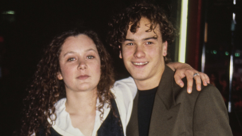 Johnny Galecki smiles as Sara Gilbert puts her arm around him.