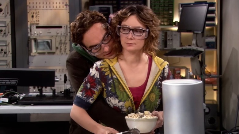 Johnny Galecki hugs Sara Gilbert from behind while filming a lab scene on "The Big Bang Theory."