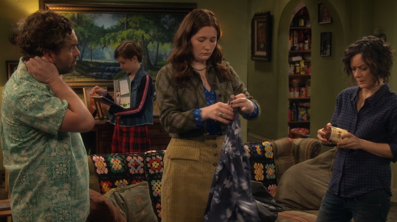 Emma Kenney stands between Johnny Galecki and Sara Gilbert and folds clothes while filming an episode of "The Conners."