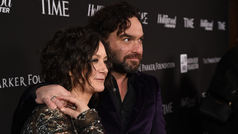 Johnny Galecki places his arm around Sara Gilbert's shoulder as she reaches up to grab his hand.