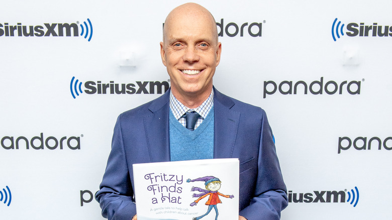 Figure skater Scott Hamilton smiles holding the children's book he wrote.
