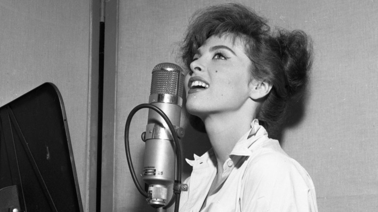 "Gilligan's Island" star Tina Louise sings into a microphone looking up in a black and white photo