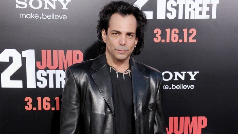 Richard Grieco posing in front of '21 Jump Street' backdrop in a leather jacket