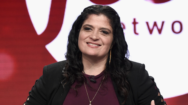 Alex Guarnaschelli smiles at an event with the Food Network logo in the background