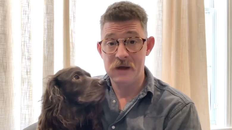 Randy Sherrell holding a dog while wearing horn-rimmed glasses