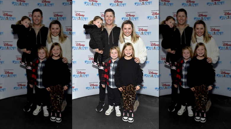 Beverley Mitchell, her husband, and their three kids bundled up in front of a Disney On Ice backdrop