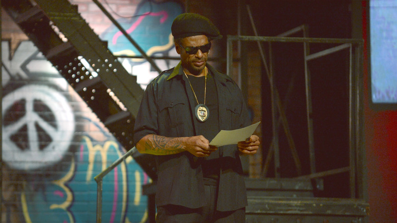 Gary Dourdan performing onstage with a police badge around his neck from a theater performance in Miami 2023