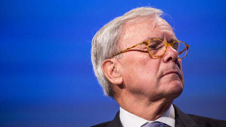Tom Brokaw wearing classes, photographed in front of a blue background