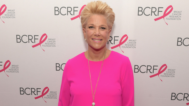 Joan Lunden posing in front of a BCRF banner in a pink dress