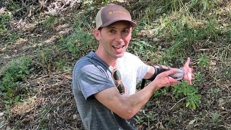Justin Berfield smiles outdoors on a grassy hill