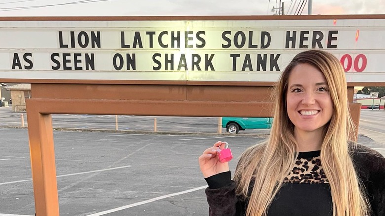 Lion Latch founder holding product in front of sign