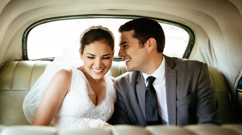 Newlyweds smiling in back of limo