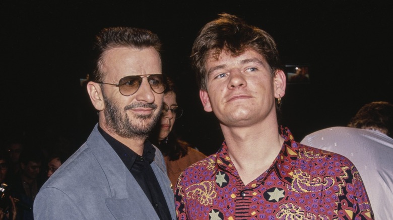 Ringo Starr in a suit smirking at Zak Starkey in a colorful shirt