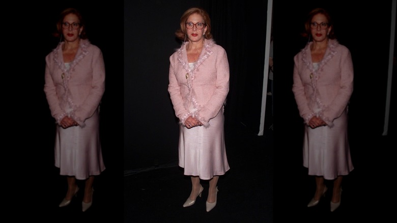 Sally Jessy Raphael in a pink overcoat and dress, looking uncomfortable