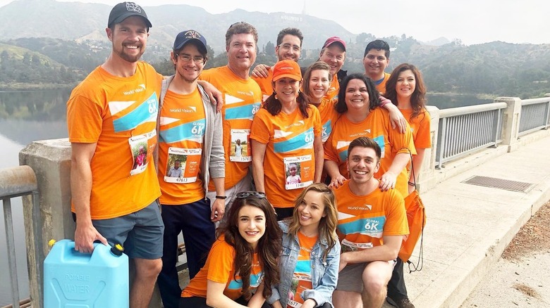 The cast of "The Middle" pose in orange shirts at a 6k smiling in front of a mountain.