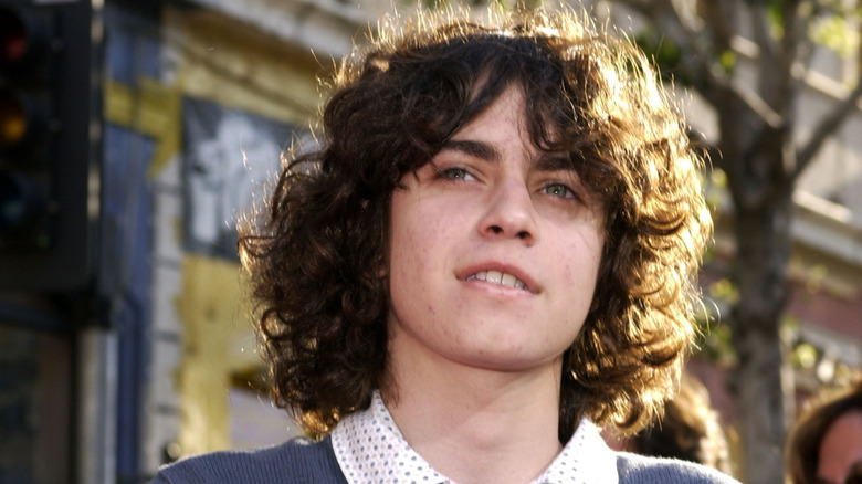 Adam Lamberg from "Lizzie McGuire" standing on a city street looking beyond the camera