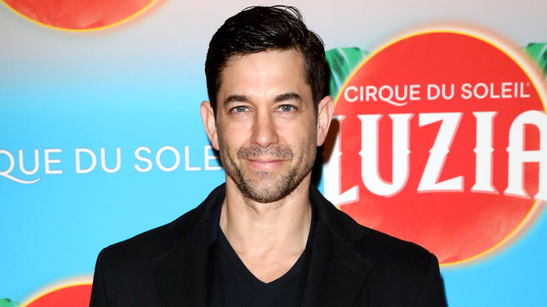 "Coyote Ugly" actor Adam Garcia smiling in all black on the red carpet at a Cirque du Soleil event