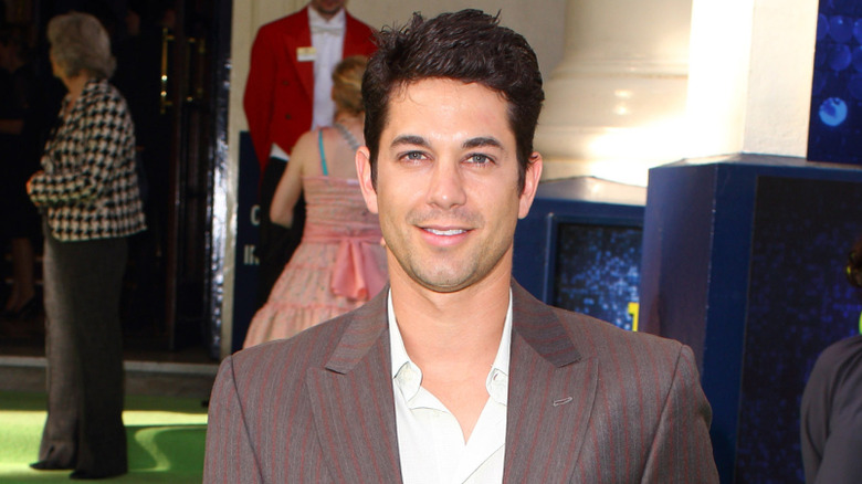 Coyote Ugly actor Adam Garcia smiling while doing press for a movie in a striped suit jacket