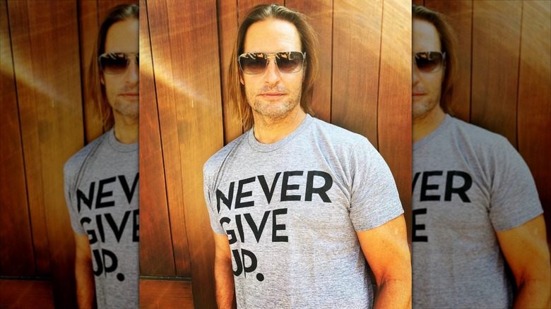 Josh Holloway wearing sunglasses and a NEVER GIVE UP shirt
