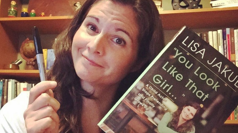Lisa Jakub smiling while holding her book