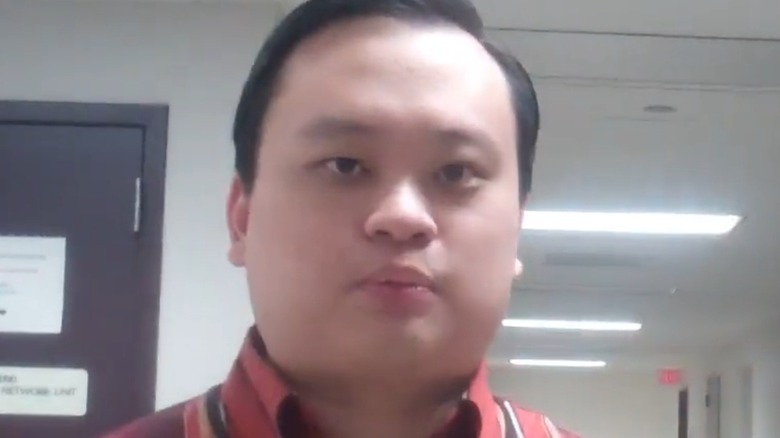 A closeup of William Hung filmed in a police station hallway