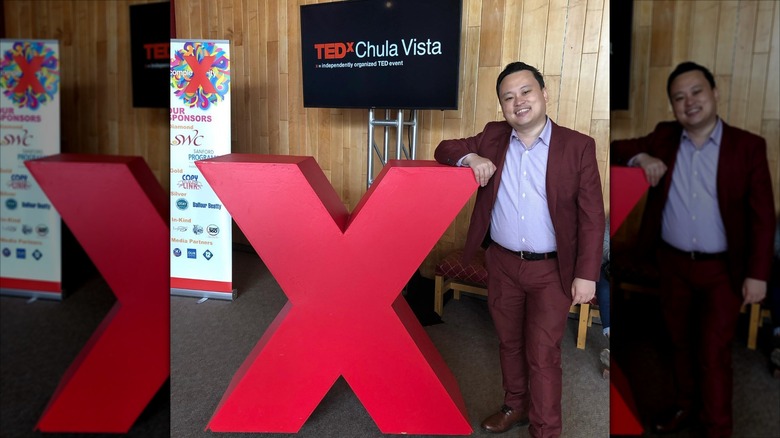 William Hung resting his arm on a big red X in front of a sign for TEDx Chula Vista