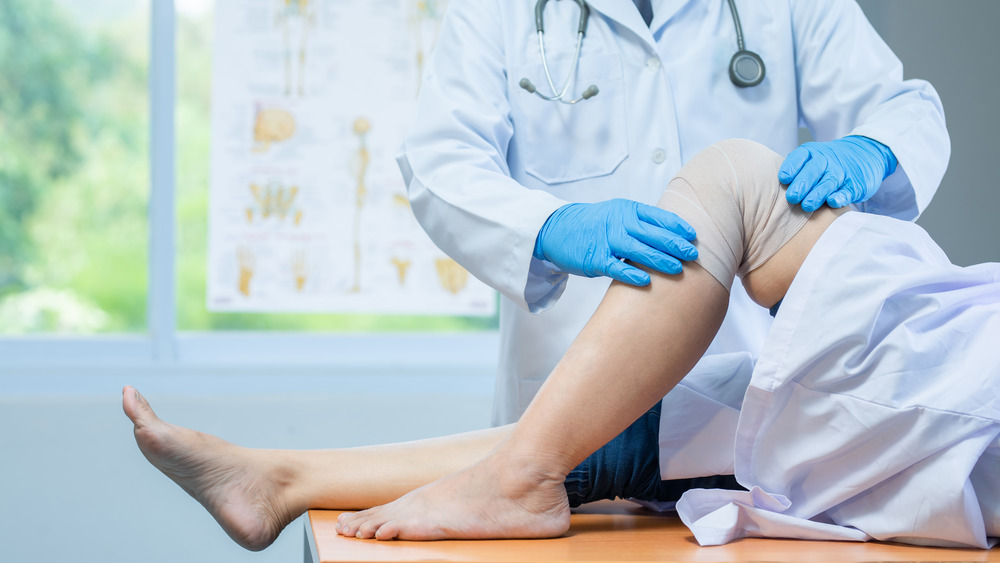 Patient getting bandaged knee examined