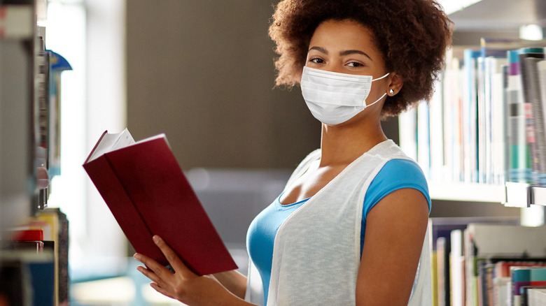 Woman reading in library with facemask