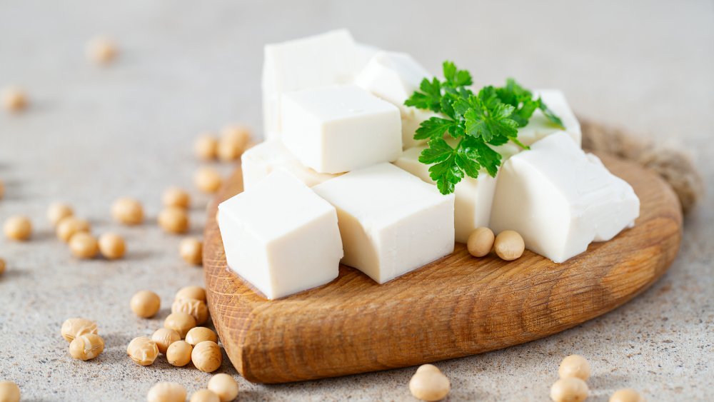 Tofu on a cutting board with herbs and beans