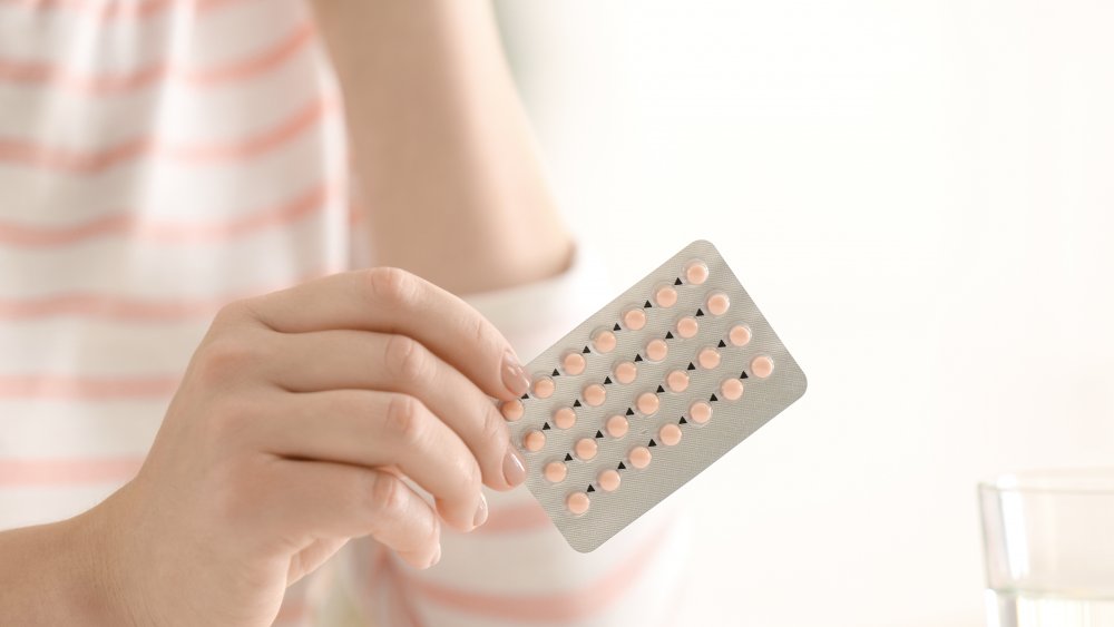 Woman holding birth control pills