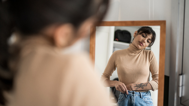 Woman fixing jeans in mirror